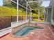 Screened-in kidney-shaped pool with waterfall feature and well-maintained brick patio and landscaping at 1180 Mesa Verde Ct, Clermont, FL 34711