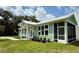 Light green house with white trim, screened in porch, and manicured landscaping at 12110 Grand Oak Ln, Oxford, FL 34484