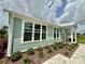 Side view of a light green house with large windows, white trim, and manicured landscaping at 12110 Grand Oak Ln, Oxford, FL 34484