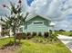 Green and white home with tidy landscaping and manicured lawn at 12110 Grand Oak Ln, Oxford, FL 34484