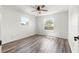 This well-lit bedroom has a ceiling fan, two windows, and clean, modern, wood-look floors at 1224 Ballesteros Dr, The Villages, FL 32162