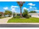 A well-maintained house with a concrete driveway, mature landscaping, and vibrant foliage at 1224 Ballesteros Dr, The Villages, FL 32162