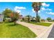 A concrete driveway leads to a lovely home with mature landscaping and a beautiful red tree at 1224 Ballesteros Dr, The Villages, FL 32162