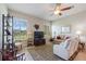 Bright living room with a ceiling fan, tile flooring, and natural light from two windows at 1351 Legendary Blvd, Clermont, FL 34711