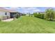Expansive backyard featuring lush green grass, mature landscaping, and screened lanai at 1721 Germakian Ln, The Villages, FL 32163