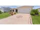 Home's driveway features a decorative compass design leading to the attached two-car garage at 1721 Germakian Ln, The Villages, FL 32163