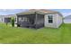 Back exterior view of the house, highlighting the screened lanai and well-maintained lawn at 1721 Germakian Ln, The Villages, FL 32163