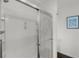 Clean shower featuring glass doors, built-in shelving, and convenient grab bars for added safety at 1721 Germakian Ln, The Villages, FL 32163