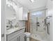 Well-lit bathroom with white cabinets, marble countertop, and accessible walk-in shower with curtain at 17824 Se 87Th Bourne Ave, The Villages, FL 32162