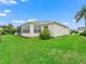 A view of the home's exterior shows an enclosed lanai and lush green yard at 17824 Se 87Th Bourne Ave, The Villages, FL 32162