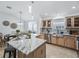 Open kitchen and dining area with island, granite counters, stainless appliances, and light wood cabinets at 17824 Se 87Th Bourne Ave, The Villages, FL 32162