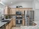 Well-lit kitchen features stainless steel appliances, light wood cabinets, and granite countertops and backsplash at 17824 Se 87Th Bourne Ave, The Villages, FL 32162