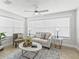 Bright living room with neutral tones, large windows, a ceiling fan, and stylish furnishings at 17824 Se 87Th Bourne Ave, The Villages, FL 32162
