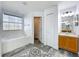 Bright bathroom featuring dual-patterned flooring, a soaking tub with natural light, and a well-lit vanity at 2019 Newtown Rd, Groveland, FL 34736