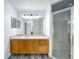 Bathroom vanity with wood cabinets, large mirror, and a glass-enclosed shower, designed for comfort and functionality at 2019 Newtown Rd, Groveland, FL 34736