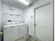 Functional laundry room equipped with a washer, dryer, and shelving for organized storage at 2019 Newtown Rd, Groveland, FL 34736