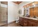 Rustic bathroom featuring a double vanity with granite counters, wood cabinetry, and tiled walk-in shower at 23247 Lake Seneca Rd, Eustis, FL 32736