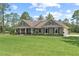 Inviting single story home featuring an expansive lawn, rocking chair front porch, and neutral exterior at 23247 Lake Seneca Rd, Eustis, FL 32736
