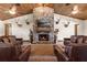 Cozy living room featuring a stone fireplace, mounted television, and comfortable leather sofas at 23247 Lake Seneca Rd, Eustis, FL 32736