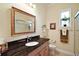A bathroom vanity boasts dark granite countertops and a decorative framed mirror at 2400 Pawtucket Pass, Mount Dora, FL 32757