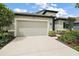 Home exterior featuring a three-car garage, well-manicured landscaping, and a modern design at 2400 Pawtucket Pass, Mount Dora, FL 32757