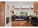 Kitchen featuring dark granite countertops, stainless steel sink, and light wood cabinets at 2400 Pawtucket Pass, Mount Dora, FL 32757