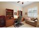 Cozy office space with built-in bookshelves, a comfortable chair, and a neutral-toned loveseat at 2400 Pawtucket Pass, Mount Dora, FL 32757