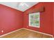 Red bedroom with hardwood floors, ceiling fan, and a window with natural light at 25025 Cranes Roost Cir, Leesburg, FL 34748
