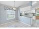 Cozy eat-in kitchen features white cabinets, tiled flooring, and a window with a floral valance at 25025 Cranes Roost Cir, Leesburg, FL 34748