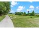 Picturesque walking path meandering through lush green grass and trees under a beautiful blue, cloud filled sky at 25025 Cranes Roost Cir, Leesburg, FL 34748