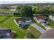 Aerial view of a landscaped home with patterned driveway near a golf course and a tranquil pond at 2557 Privada Dr, The Villages, FL 32162