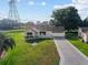Aerial view of a well-maintained property with a lush lawn and a patterned driveway leading to an attached garage at 2557 Privada Dr, The Villages, FL 32162