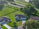 Aerial view shows manicured lawn, patterned driveway of a home near a wooden fence, golf course, and pond at 2557 Privada Dr, The Villages, FL 32162