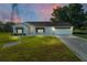 Charming home with manicured lawn, attached two car garage, and sunset sky backdrop at 2557 Privada Dr, The Villages, FL 32162