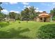 Expansive green backyard featuring a covered carport next to a house, and a garage in the distance at 27113 Robertson Rd, Yalaha, FL 34797