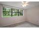 Bright bedroom with large window overlooking lush greenery and ceiling fan at 27113 Robertson Rd, Yalaha, FL 34797