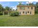 A spacious lawn surrounds this two-story home with a covered parking area and multiple back doors at 27113 Robertson Rd, Yalaha, FL 34797