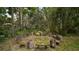 Secluded outdoor fire pit area surrounded by mature trees and seating at 27113 Robertson Rd, Yalaha, FL 34797