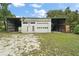 A garage with a white door surrounded by open storage areas on both sides stands on a lawn in this property image at 27113 Robertson Rd, Yalaha, FL 34797
