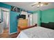 Vibrant bedroom with turquoise walls, a ceiling fan, and a doorway to a bathroom at 27212 Orange Ave, Yalaha, FL 34797