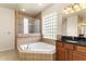 Well-lit bathroom featuring a tiled shower, soaking tub, glass block window, and vanity with dark countertop at 29152 David Ct, Tavares, FL 32778