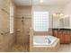 Beautiful bathroom with tiled shower, soaking tub, glass block window, and vanity with dark countertop at 29152 David Ct, Tavares, FL 32778