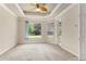 Bright bedroom featuring a tray ceiling, large window overlooking the yard, and a door leading to the patio at 29152 David Ct, Tavares, FL 32778
