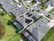 Aerial shot of a house featuring solar panels and a screened-in pool, set in a community near a lake at 3021 King Palm Dr, New Smyrna Beach, FL 32168