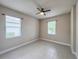 Neutral bedroom with two windows, a ceiling fan and light tile flooring at 3021 King Palm Dr, New Smyrna Beach, FL 32168