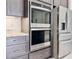 Kitchen with stainless steel Whirlpool double oven, refrigerator, gray cabinetry, and marble countertops at 3021 King Palm Dr, New Smyrna Beach, FL 32168