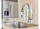 Stainless steel kitchen sink with pull down faucet, marble counters, stainless refrigerator and exterior view at 3021 King Palm Dr, New Smyrna Beach, FL 32168