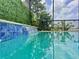 Beautiful pool with a mosaic-tiled waterfall feature and lush greenery at 3021 King Palm Dr, New Smyrna Beach, FL 32168