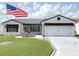 Charming one-story home with a manicured lawn, an American flag, a two-car garage, and a delightful screened in porch at 3237 Atwell Ave, The Villages, FL 32162