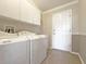 Bright laundry room featuring a washer, dryer, cabinetry, sink and access to the exterior at 3237 Atwell Ave, The Villages, FL 32162